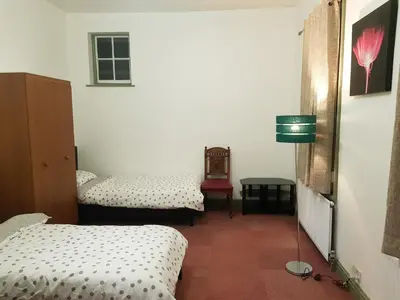 a room with two beds and a table with a lamp at Costa Suite in Ipswich