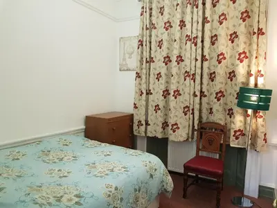 a bedroom with a bed and a red chair at Costa Suite in Ipswich