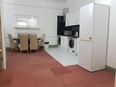 a kitchen with a table and a white refrigerator at Costa Suite in Ipswich