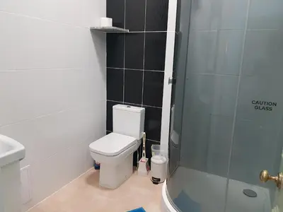 a bathroom with a toilet and a glass shower at Costa Suite in Ipswich