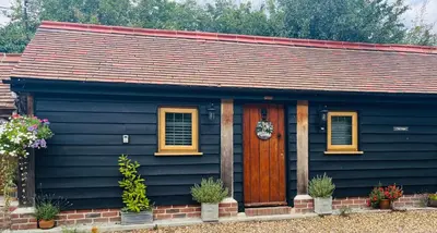 a blue house with a brown door and windows at The Lodge in Little Clacton