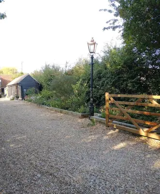 a wooden gate and a street light next to a road at The Lodge in Little Clacton