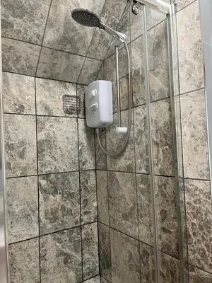 a shower with a shower head in a bathroom at The Lodge in Little Clacton