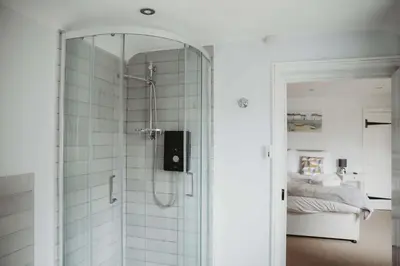 a bathroom with a shower with a mirror and a bed at Hazel's in Leiston