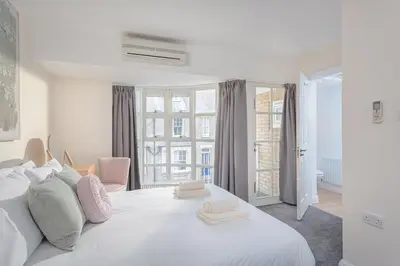 a white bedroom with a large white bed and windows at 3 Bedroom Jesus Green Townhouse with Parking in Cambridge