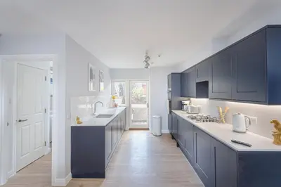 a kitchen with blue cabinets and a white counter top at 3 Bedroom Jesus Green Townhouse with Parking in Cambridge
