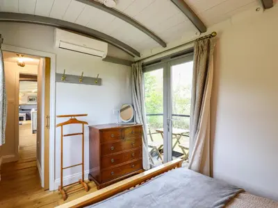 a bedroom with a bed and a dresser and a window at The Carriage at High Barn Heritage in Halstead