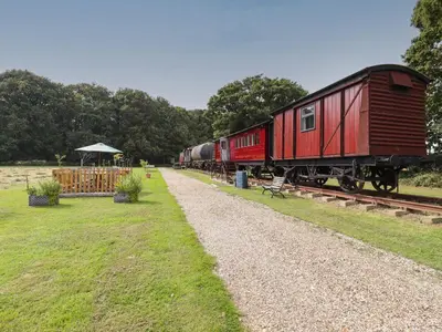 a red train is parked on the tracks at The Carriage at High Barn Heritage in Halstead