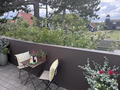 a patio with a table with a bottle of wine and chairs at Regatta - A lakeview apartment in Thorpeness - Aldeburgh Coastal Cottages in Thorpeness