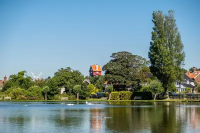 a large lake with a house in the background at Regatta - A lakeview apartment in Thorpeness - Aldeburgh Coastal Cottages in Thorpeness