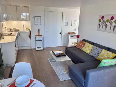 a living room with a couch and a kitchen at Regatta - A lakeview apartment in Thorpeness - Aldeburgh Coastal Cottages in Thorpeness