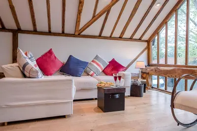 a living room with a white couch with colorful pillows at The Hayloft, Clopton in Clopton