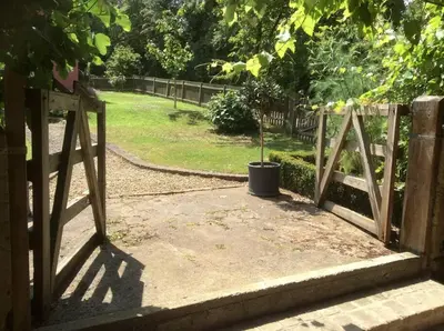 a wooden gate with a potted plant in a garden at The Hayloft, Clopton in Clopton