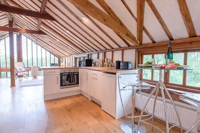 a kitchen with white appliances and wooden ceilings at The Hayloft, Clopton in Clopton