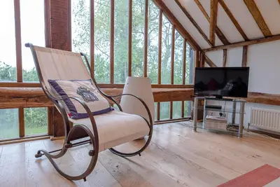 a rocking chair in a room with a television at The Hayloft, Clopton in Clopton
