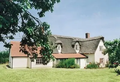 a large white house with a gray roof at Burnt House Cottage in Barking