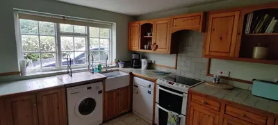 a kitchen with wooden cabinets and a washer and dryer at Burnt House Cottage in Barking