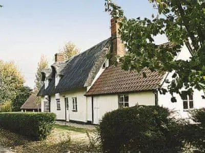 a white house with a black roof at Burnt House Cottage in Barking