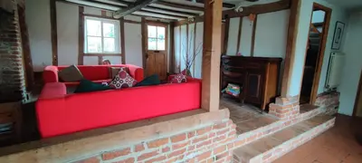 a red couch in a room with a fireplace at Burnt House Cottage in Barking