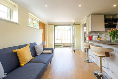 a living room with a blue couch and a kitchen at Foxes Lodge in Aldringham