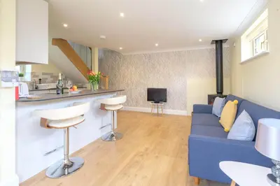 a living room with a blue couch and a kitchen at Foxes Lodge in Aldringham