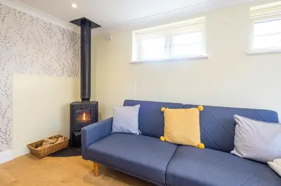 a blue couch in a living room with a stove at Foxes Lodge in Aldringham
