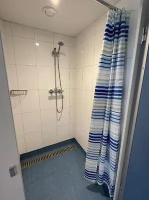 a shower with a blue and white curtain in a bathroom at The Old Dairy Accommodation in Tillingham
