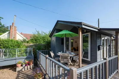 a small house with a table and an umbrella at 1 Bed in Waldringfield oc-thstu in Waldringfield