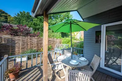 a patio with a table and a green umbrella at 1 Bed in Waldringfield oc-thstu in Waldringfield