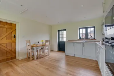 a kitchen with a table and chairs and a wooden door at 2 Bed in Weybread oc-tclwey in Needham