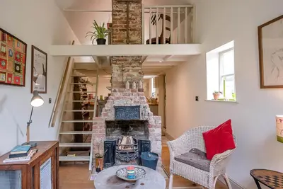 a living room with a stone fireplace and a table at The Wash House, Middleton in Saxmundham