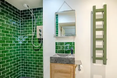 a bathroom with green subway tiles and a sink at The Wash House, Middleton in Saxmundham