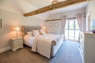 a bedroom with a bed and a large window at Chapel Cottage at Pond Hall Farm, Stunnning Property with Private Hot Tub, Hadleigh in Ipswich