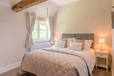 a bedroom with a large bed and a window at Chapel Cottage at Pond Hall Farm, Stunnning Property with Private Hot Tub, Hadleigh in Ipswich