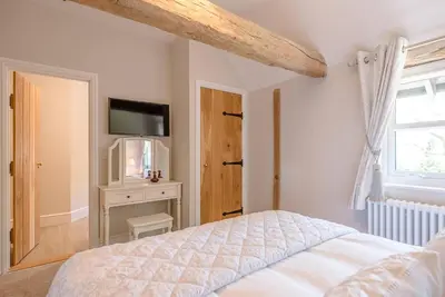 a bedroom with a bed and a tv and a window at Chapel Cottage at Pond Hall Farm, Stunnning Property with Private Hot Tub, Hadleigh in Ipswich