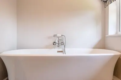 a white bath tub in a bathroom with a window at Chapel Cottage at Pond Hall Farm, Stunnning Property with Private Hot Tub, Hadleigh in Ipswich