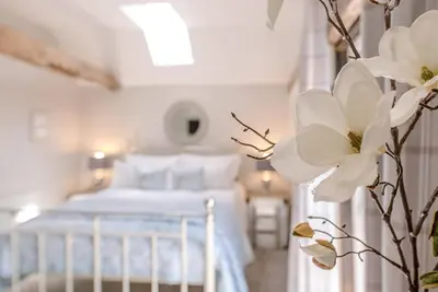 a bedroom with a white bed and a white flower at Chapel Cottage at Pond Hall Farm, Stunnning Property with Private Hot Tub, Hadleigh in Ipswich