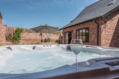 a hot tub with a glass of wine and an umbrella at Chapel Cottage at Pond Hall Farm, Stunnning Property with Private Hot Tub, Hadleigh in Ipswich