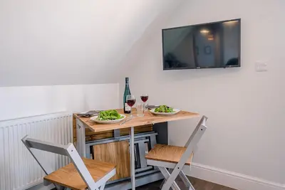 a small table with two chairs and a television on a wall at Geoff's Rest at Pond Hall Farm in Hadleigh with Private Hot Tub in Ipswich