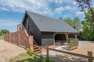 a small black building with a brick wall at Geoff's Rest at Pond Hall Farm in Hadleigh with Private Hot Tub in Ipswich