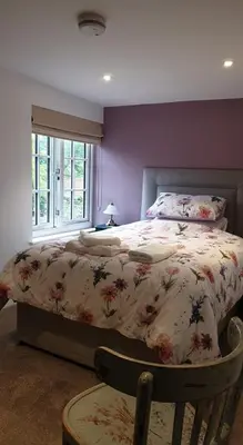 a bedroom with a bed with a floral bedspread and a window at Argyll House Bed and Breakfast in Westleton