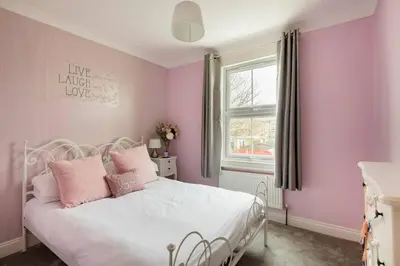 a bedroom with pink walls and a bed with pink pillows at A Wave From It All in Great Clacton