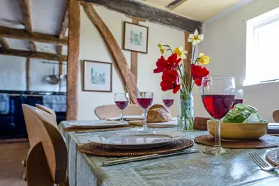 a table with red flowers and wine glasses on it at Heart's Ease in Dallinghoo nr Woodbridge in Woodbridge