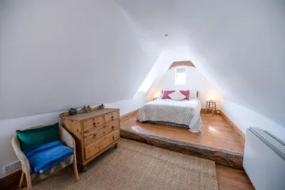 a bedroom with a bed and a chair in a attic at Heart's Ease in Dallinghoo nr Woodbridge in Woodbridge