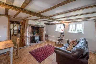 a living room with a leather couch and a fireplace at Heart's Ease in Dallinghoo nr Woodbridge in Woodbridge