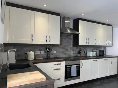 a kitchen with white cabinets and a sink at Juniper House in Harwich