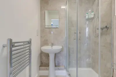 a bathroom with a sink and a glass shower at Juniper House in Harwich