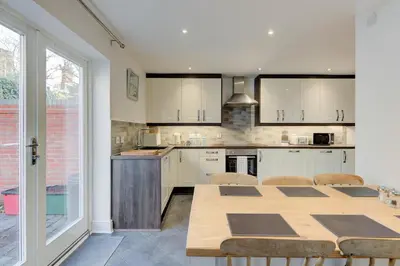 a kitchen with white cabinets and a table with chairs at Juniper House in Harwich