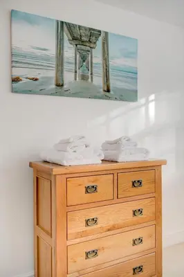 a painting of a pier and a wooden dresser at Juniper House in Harwich