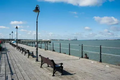 a pier with benches and a street light and the water at The Lookout Penthouse in Harwich